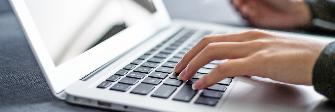 
Ruce zadávají na laptopu údaje pro účely zaúčtování on-line
