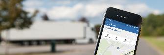 
Na displeji smartfónu sa zobrazuje aplikácia Toll Collect. V pozadí parkuje nákladné vozidlo.