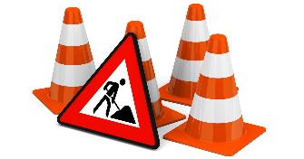 
A "Baustelle" (roadworks) road sign stands next to some warning cones.