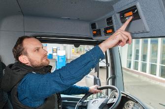 
In a truck cab, a driver operates an OBU