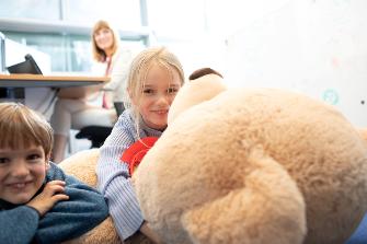 
Eine Mutter arbeitet im Eltern-Kind-Büro, ihre Tochter spielt mit einem Teddybären