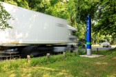 
Un camión circula por una carretera nacional junto a una columna de control azul de Toll Collect.