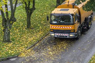 
Транспортное средство для уборки улиц, не облагаемое дорожным сбором, подметает листву деревьев